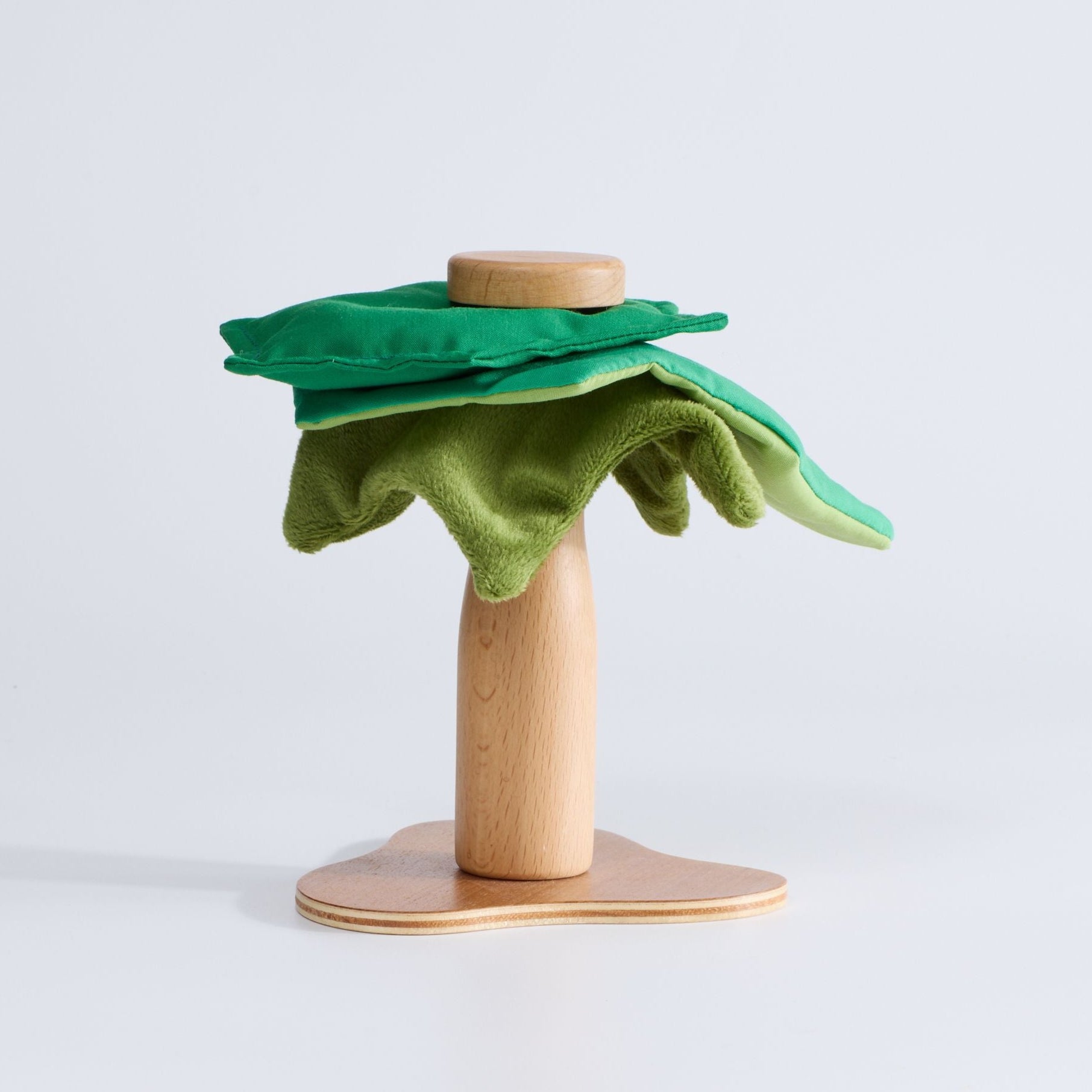 Wooden toy with green felt leaf on light gray background