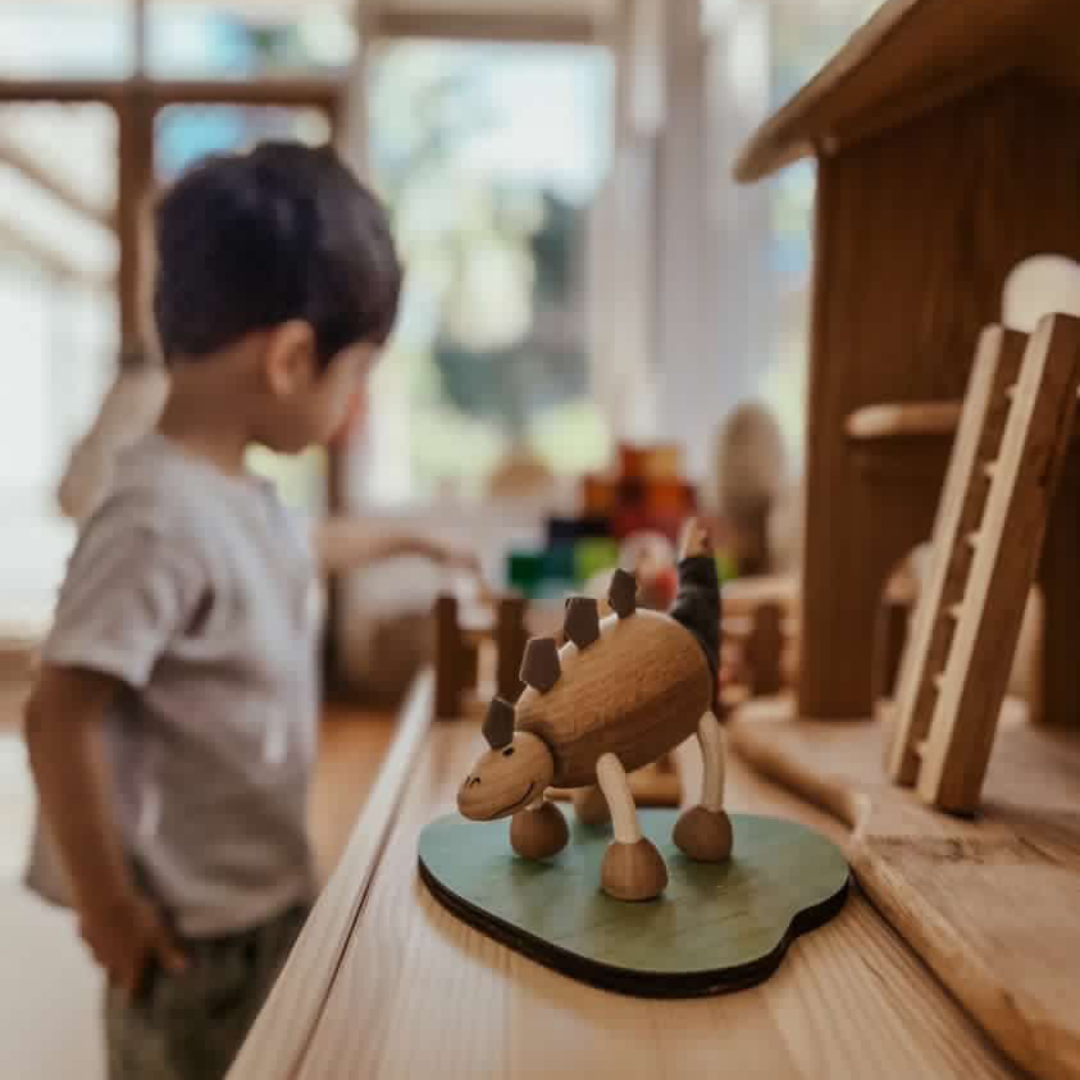 wooden stegosaurus toy on a table with a small boy in the background playing
