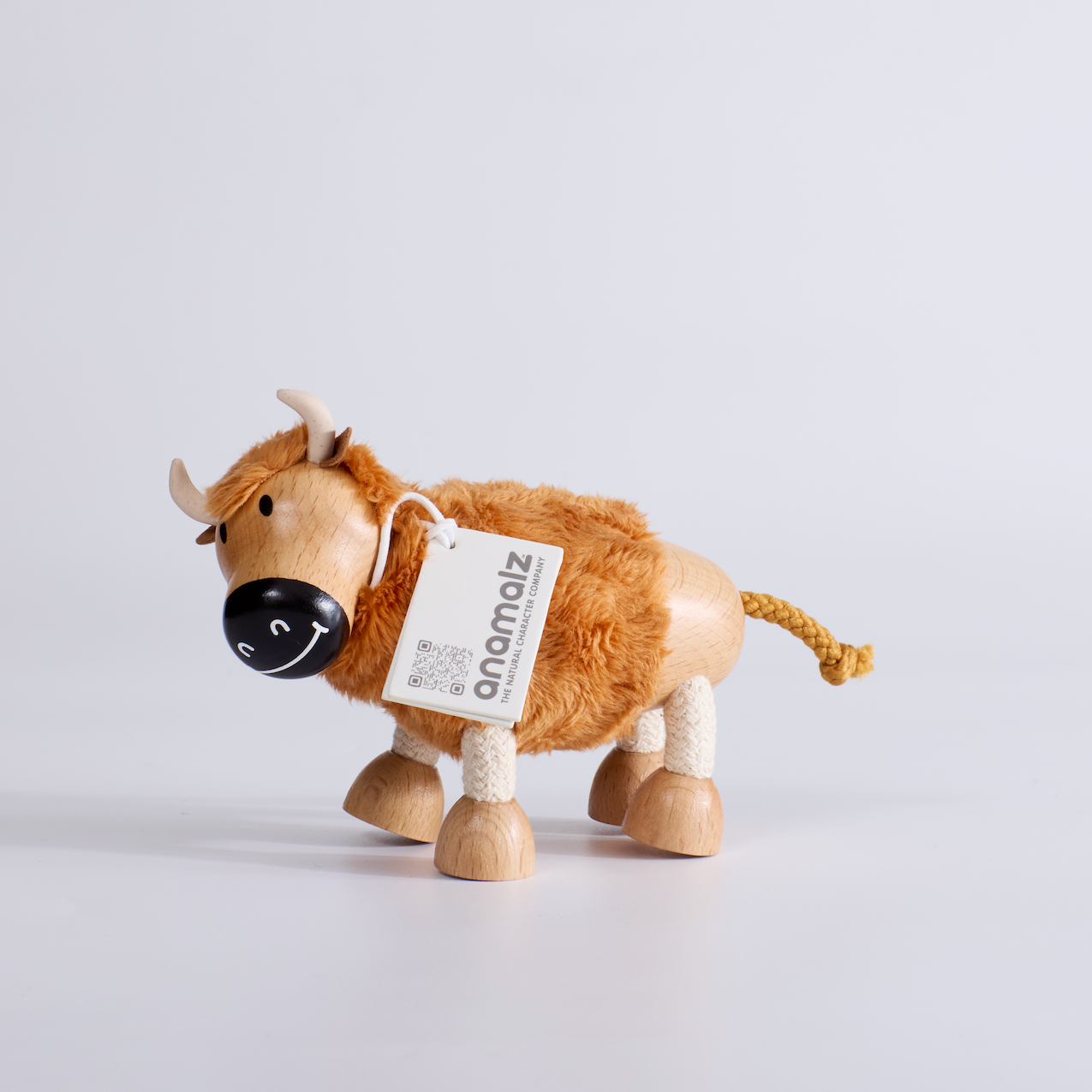 Wooden toy yak with a tag on a light gray background