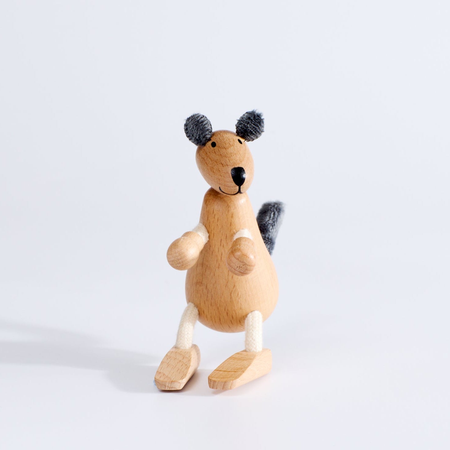 A wooden toy kangaroo with plush fabric and rope, standing upright on a white background.