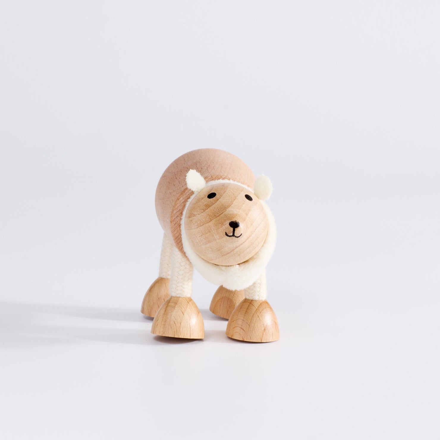 A wooden polar bear toy with a happy facial expression, standing upright on a white background.