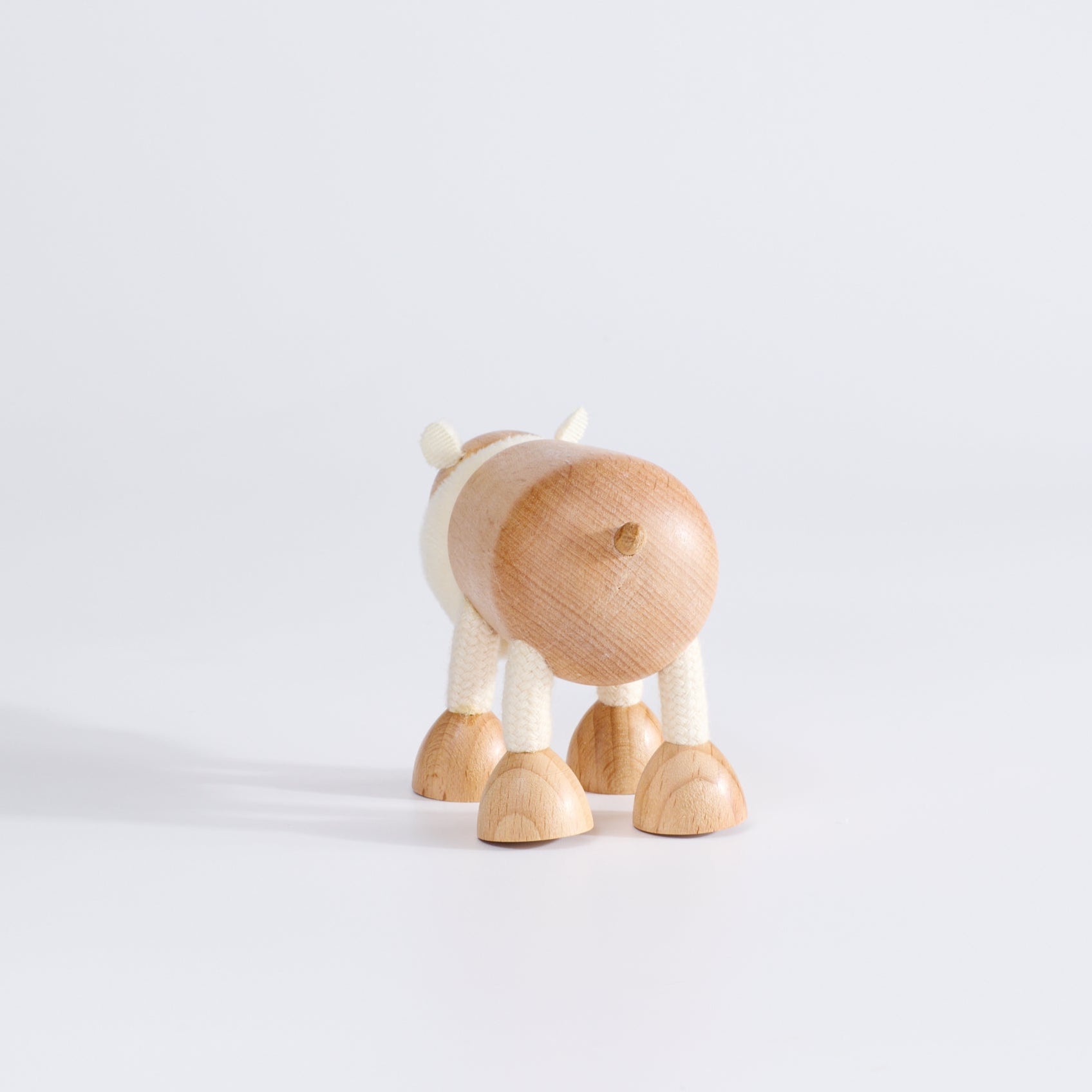 A wooden polar bear toy facing backwards, standing upright on a white background.