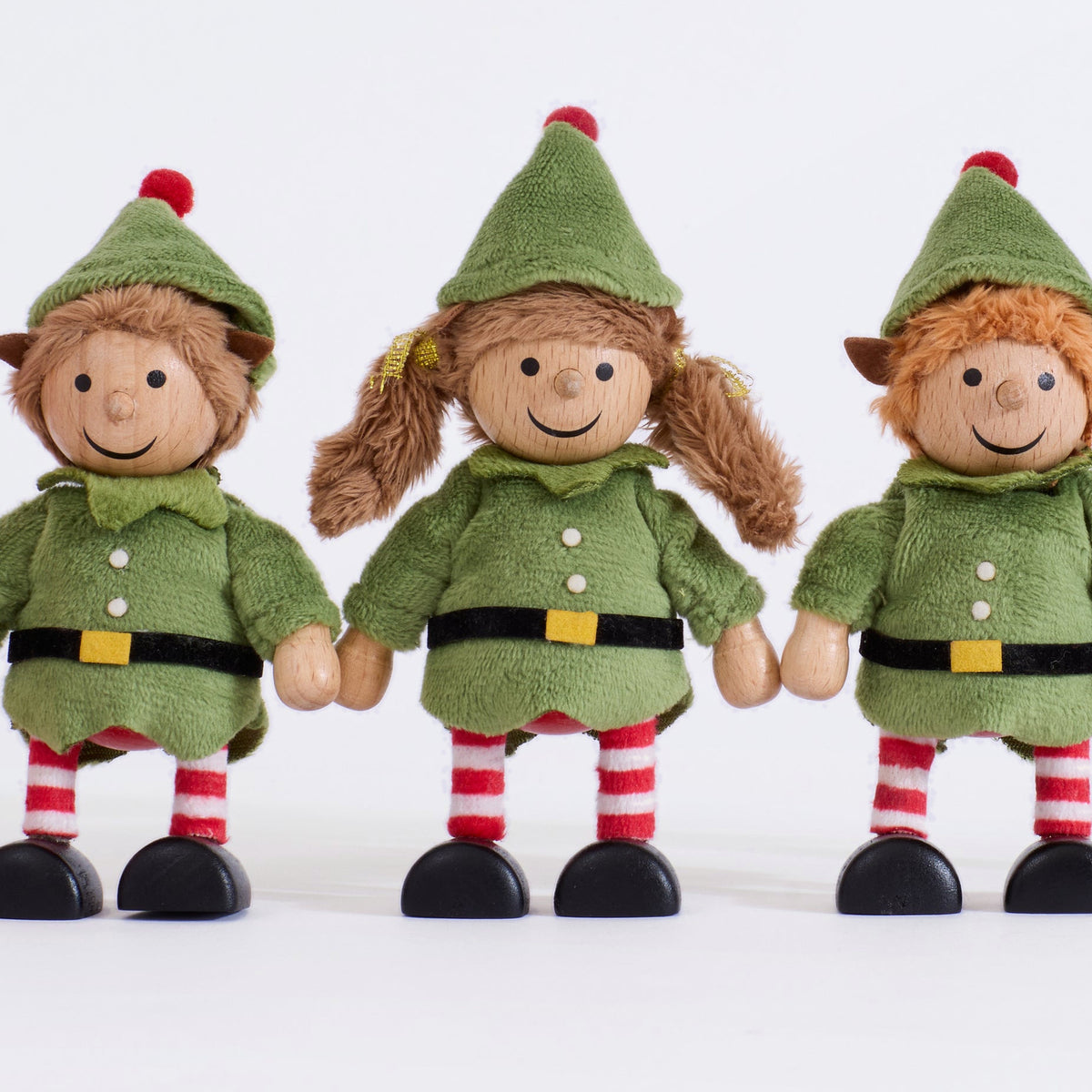 Close-up of the three Cheeky Elves showing their wooden faces, green outfits and striped legs