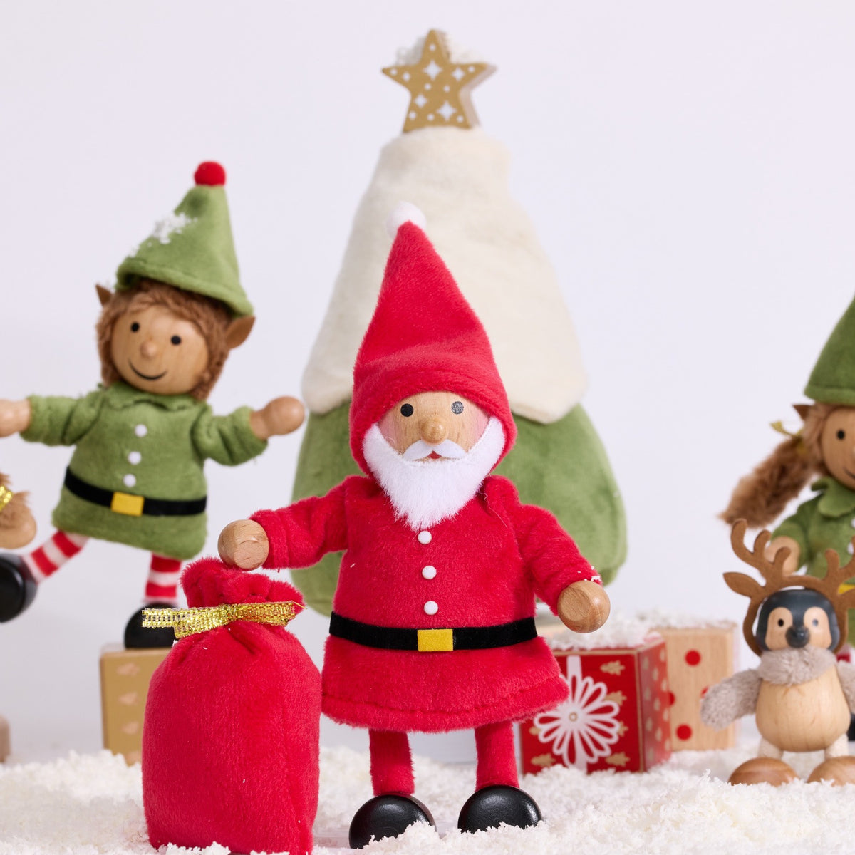 Cheery Santa standing beside a red sack and Christmas tree in a snowy festive scene