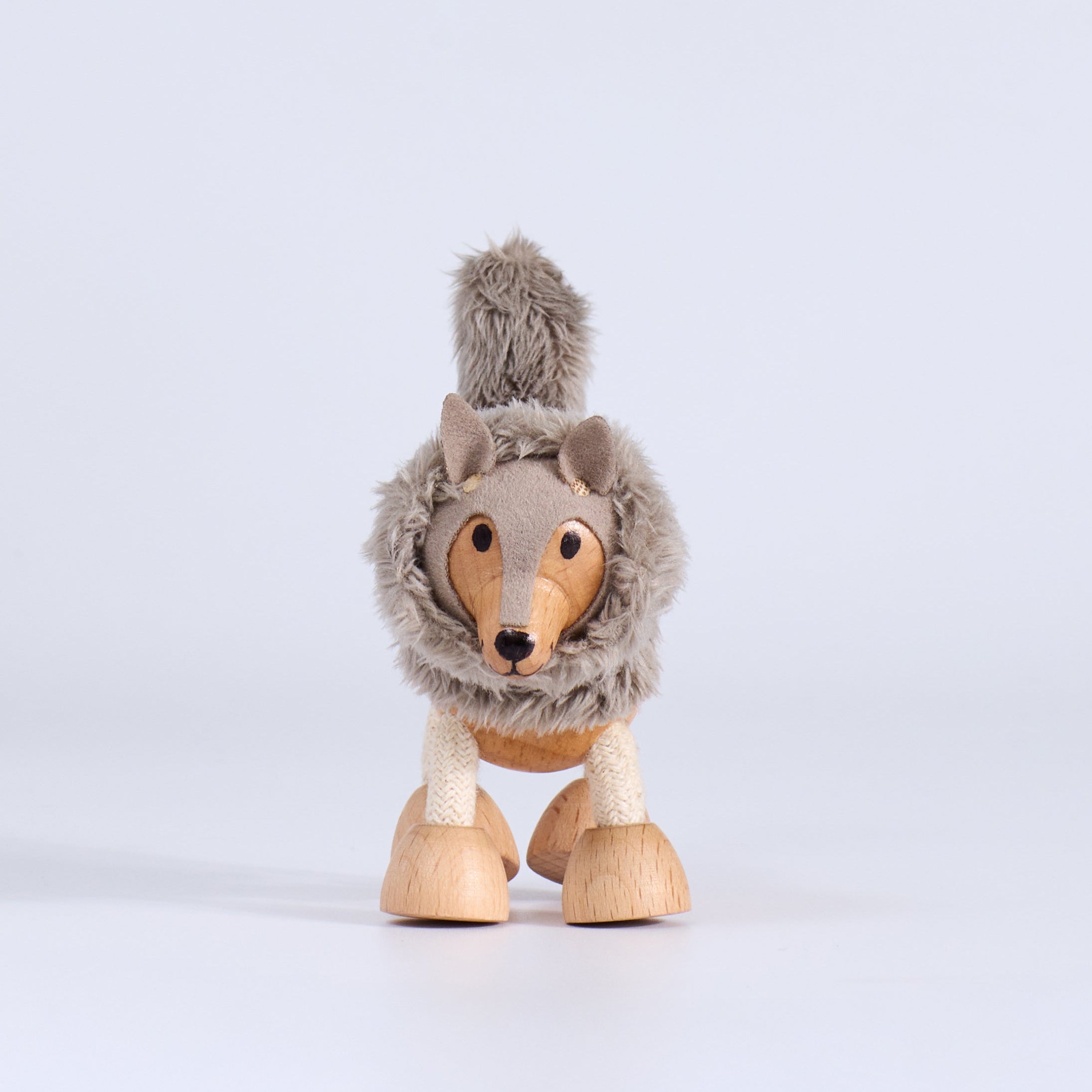 Wooden toy figure of a wolf with a fur coat on a white background