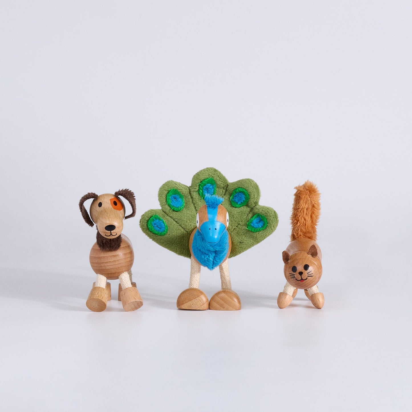 Three wooden animal figurines dog, peacock and cat on a white background