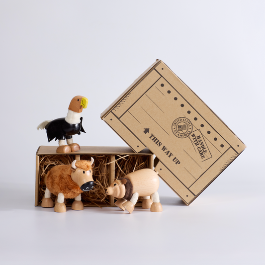 Wooden animal figurines on a cardboard box labeled 'Wild Transport' against a white background