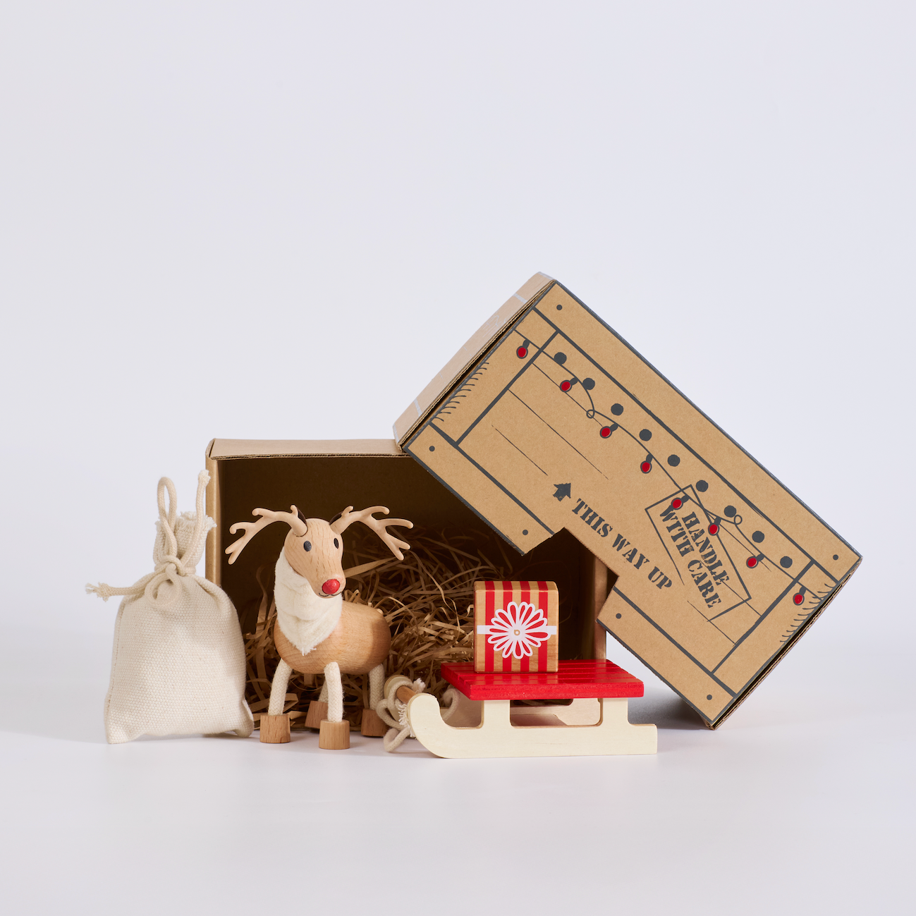 Small decorative reindeer and bag with a cardboard box on a light gray background