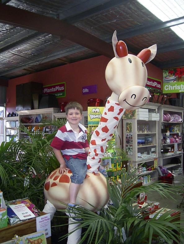 a boy sitting on the back of toy giraffe statue