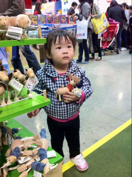 small child holding wooden moose toy in a toy store