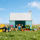 Anamalz Barnfields gift card artwork with a teal barn, farmer and wooden farm toys under a blue sky